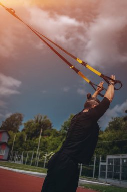 Genç sporcu ya da vücut geliştirici Trx 'le spor yapıyor.