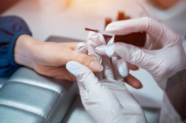 Yakın çekim ve manikür sanatçısı tırnak temizleme ve cilalama yapıyor.