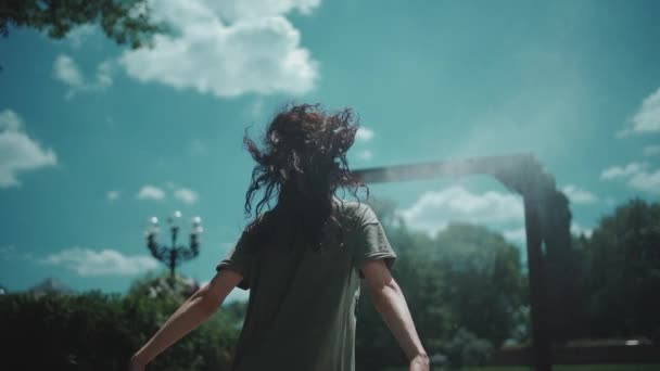 Enfriamiento femenino joven y hermoso en el marco del aerosol del agua en el parque público de la naturaleza — Vídeos de Stock