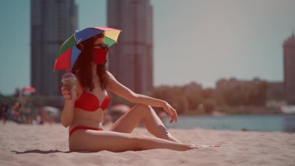 Joven hembra sentada en la playa urbana en máscara médica y bebidakg mojito cocktail — Vídeo de stock
