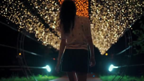 Emotioneel krullend haar brunette dame glimlach en wandelen in de stad nacht licht buiten — Stockvideo