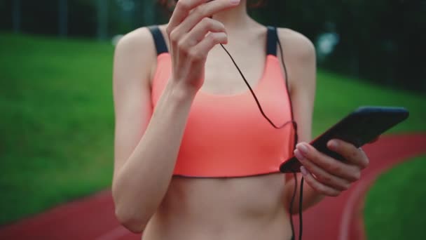 Young female runner listening music with headphones outdoor after sport exercise — Stock Video