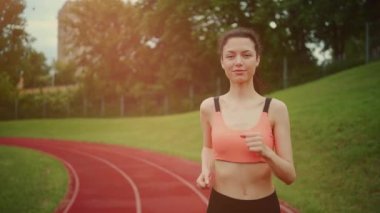 Güneşli bir sabahta dışarıda koşan ve antrenman yapan atletik bir kadın.