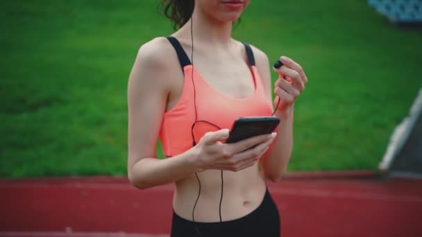 Молода жінка бігунка слухає музику з навушниками на відкритому повітрі після спортивних вправ — стокове відео