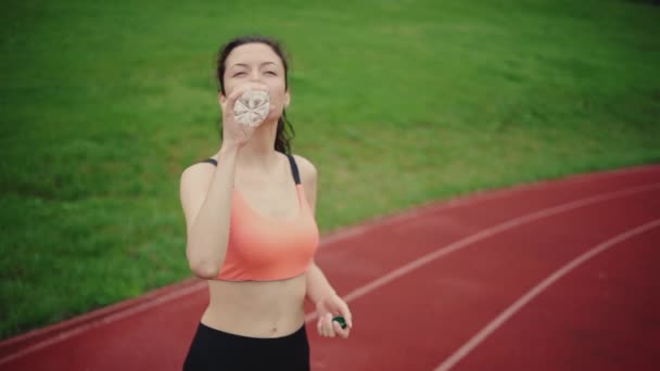 Atletická žena jogger pít vodu po tréninku na stadionu — Stock video