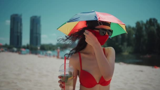Joven hembra sentada en la playa urbana en máscara médica y bebidakg mojito cocktail — Vídeo de stock
