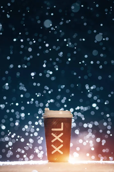 Велика паперова чашка з чаєм або кавою на падаючому сніговому фоні вночі — стокове фото