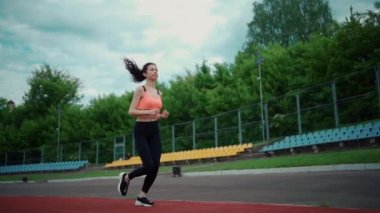 Atletik kadın yazın dışarıda koşuyor ve antrenman yapıyor.