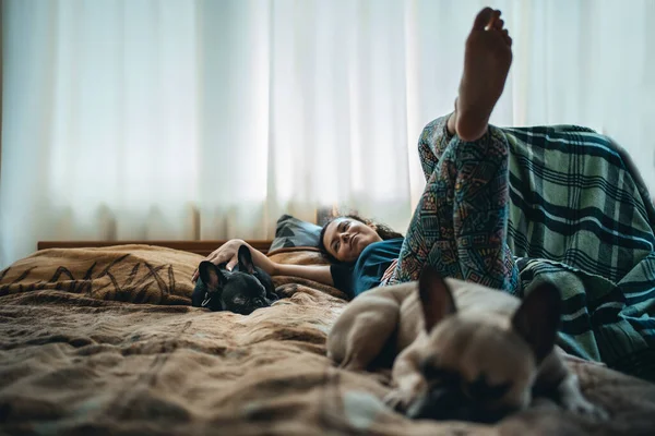 Жінка відпочиває з парою милих французьких бульдог домашніх тварин на ліжку вдома — стокове фото