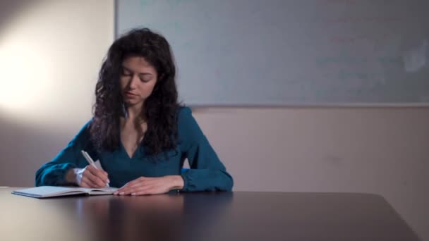 Wanita berambut cokelat keriting membuat catatan di kelas sekolah — Stok Video