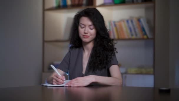 Curly brunette woman making notes in school classroom — Stock Video