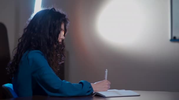 Curly brunette woman making notes in school classroom — Stock Video
