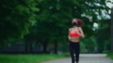 aktif ve genç esmer kadın sabah parkında maskeyle koşuyor.