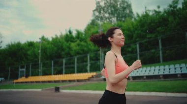 Atletik kadın yazın dışarıda koşuyor ve antrenman yapıyor.