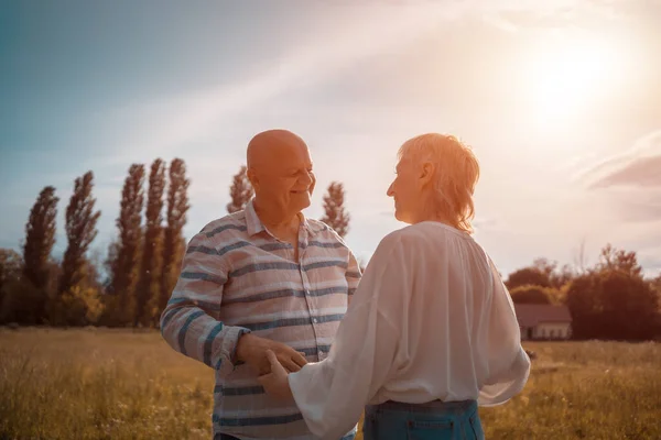 Happy senior couple dating, hugging and kissing outdoor at sunset — Stock Photo, Image