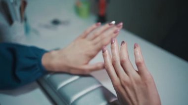Manikür sanatçısı fırça ve aletlerle tırnak cilası yapıyor