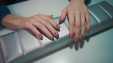 Manikür sanatçısı fırça ve aletlerle oje yapmış.