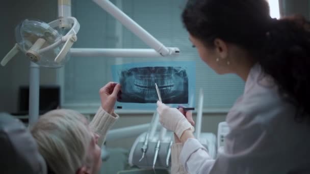 Profissional dentista feminino mostrar imagem de raios-x da boca panorâmica para o paciente — Vídeo de Stock