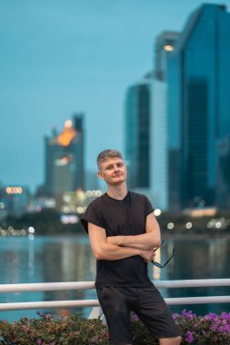 Canlı bir gece şehrinde, gökdelenlerin arka planında yakışıklı bir adam. Parlak şehir siluetiyle poz veren şık bir adam. Yüksek kalite fotoğraf