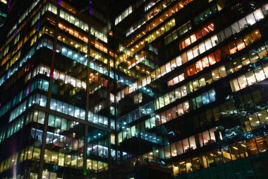 Windows ofislerin birbirine yansıtır. Burada çalışma gece, çok renkli penceresini ışıklara, beyaz, turuncu devam eden çok sayıda ofisler cam yüzeylerde yansıtılır.
