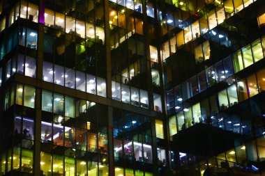 Ofis Binası geceleri. Burada çalışma gece, çok renkli penceresini ışıklara, beyaz, turuncu, koyu siluetleri binanın devam eden çok sayıda binalar.