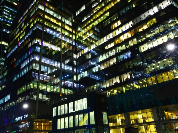 Ofis windows geceleri. Burada çalışma gece, çok renkli penceresini ışıklara, beyaz, koyu bina toplu bir sürü windows ile devam eden çok sayıda ofisler.