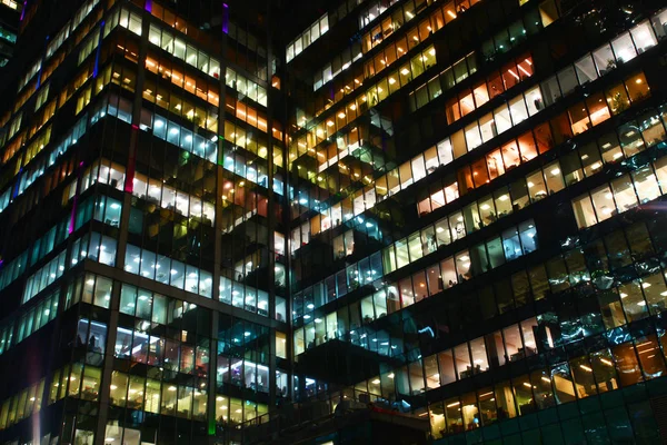 Windows ofislerin birbirine yansıtır. Burada çalışma gece, çok renkli penceresini ışıklara, beyaz, turuncu devam eden çok sayıda ofisler cam yüzeylerde yansıtılır.