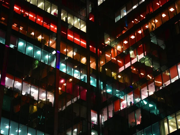 Burada çalışma gece, çok renkli penceresini ışıklara, beyaz, turuncu, koyu siluetleri binanın devam eden çok sayıda binalar.