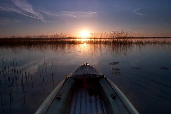 Dawn, The bow of the boat is directed towards the sun rising above the lake