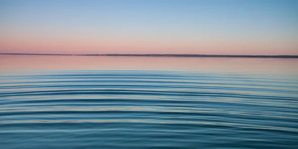 黎明时的绿松石湖 在黎明时 蓝色和绿松石湖表面的小对称波浪 红色和橙色和天空蓝色 — 图库照片