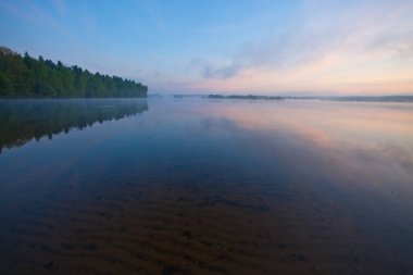 Gölde şafak. Su ile ön planda kum, su, mavi ve kırmızı gökyüzü sakin yüzeyine görebilirsiniz