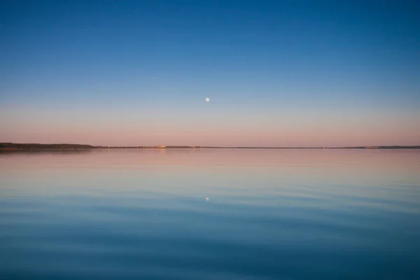 The turquoise dawn.Russia, Yaroslavl region, the city of Pereslavl, Pleshcheyevo lake. smooth blue and turquoise lake surface at dawn, red and orange and sky blue.