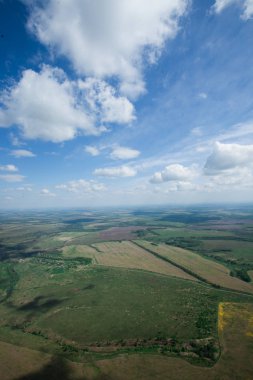 Alanlar ve bulutlar. Havadan görünümü büyük bir yükseklikten. Bulutlar, gölgelerin içinden bulutlar, yol.
