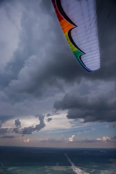 O parapente sob as nuvens de trovão, a asa multicolorida — Fotografia de Stock