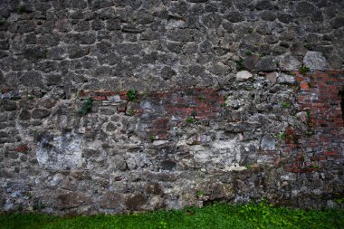 Gri taş ve yeşil çim kaotik döşeme antik karanlık duvarına. arka plan