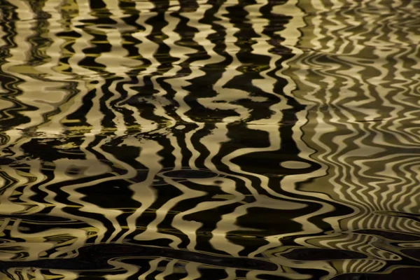 Hedvábný povrch vody se zlatými pruhy a vlny, pozadí tex — Stock fotografie