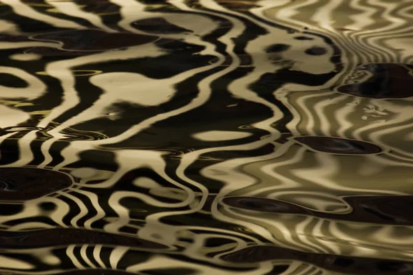 The golden surface of the water has a silk (velvet) texture, the — Stock Photo, Image