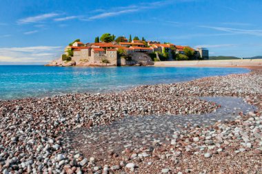 Kırmızı kiremitlerle kaplı eski evler ve parlak mavi deniz, yakın plan. 