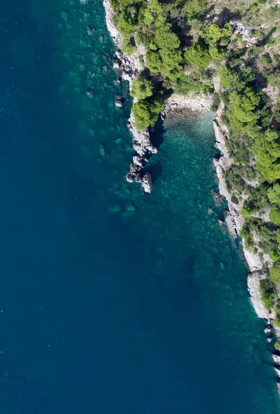Kamienny klif z krzakami w morzu i łódką, od góry do dołu — Zdjęcie stockowe