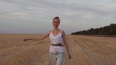 Kız tarlada mutlu bir şekilde yürüyor.
