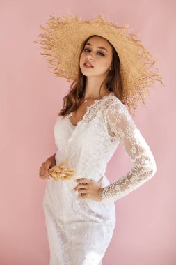 Pembe arka planda saman şapkalı mutlu bir portre.