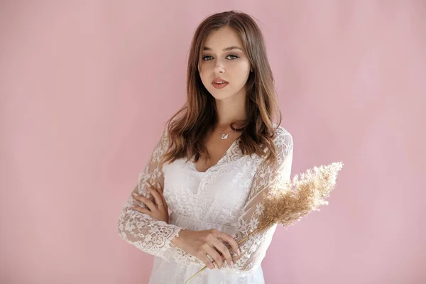 Elinde buğdayla pembe arka planda bir kız.