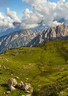 Sarp kayalıklı tepeleri, canlı yeşil vadileri, derin mavi gökyüzü olan Dolomitlerin ikonik dikey görüntüsü. Kuzey İtalya 'nın nefes kesici alp manzarası, seyahat için ideal, doğa teması.