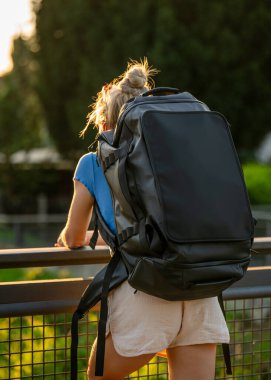 Şortlu, sırt çantalı, şehir köprüsünde duran genç bir kadının arka görüntüsü. Şehir keşfi, solo seyahat, bağımsızlık, modern yaşam tarzı konsepti.