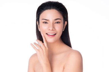 Güzel, genç Asyalı bir kadın yumuşak yanak gülümsemesine dokunuyor. Temiz ve taze tenli. Mutluluk ve neşe dolu.