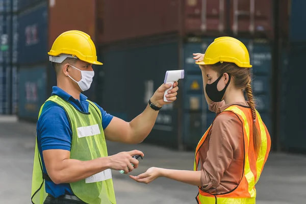 Engineer worker waring surgical mask checking body temperature using infrared digital thermometer check temperature before into work place,