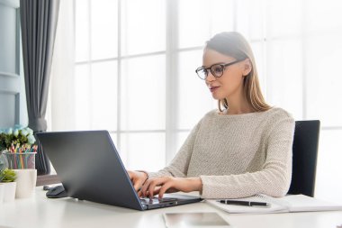 Güzel bir kadın evde dizüstü bilgisayarıyla çalışıyor.