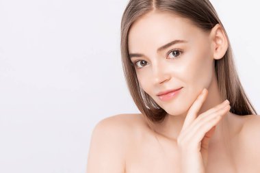 Güzel, genç bir kadın temiz yüzüne dokunuyor. Sağlıklı cilt, beyaz arka planda izole edilmiş güzellik kozmetik ve yüz bakımı konsepti..