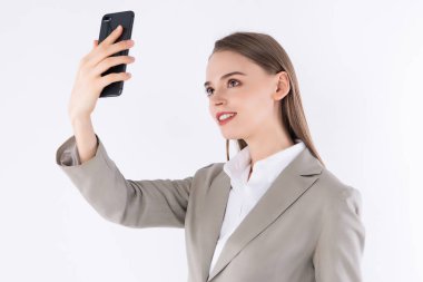 Beyaz bir arka planda izole edilmiş akıllı telefondan selfie çeken çekici bir kadının portresi.,