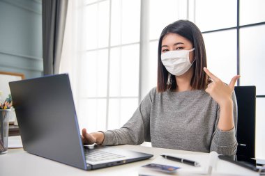 Asyalı çalışan kadın yüz maskesiyle labradoru üzerinde çalışıyor. Evde rahatça çalışıyorum. Ofiste çalışıyorum..